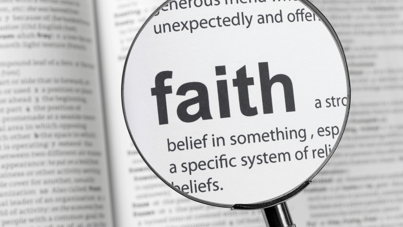 Magnifying glass laid over printed word 'Faith'