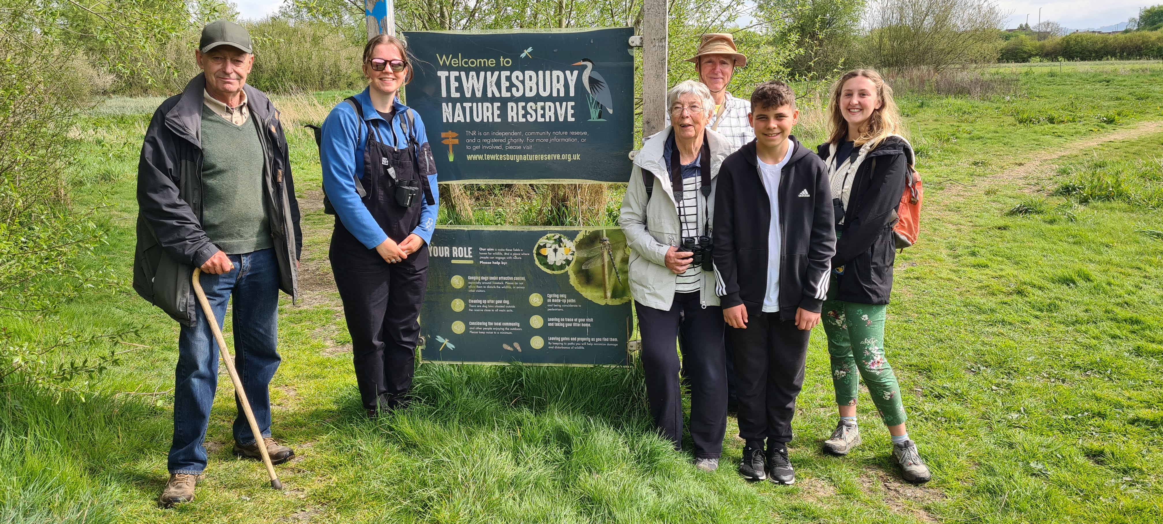 Tewkesbury Nature reserve team standing in a field at the Reserve together and smiling at the camera.